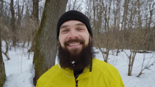 Zbliżenie Portret brodatego człowieka z niebieskimi oczami śmiejąc się zimą Las — Wideo stockowe