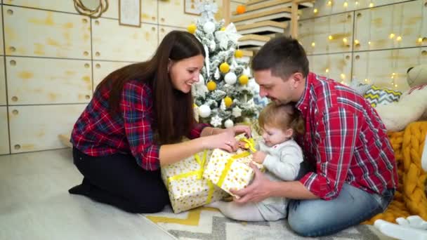 Familia feliz con hija pequeña desempacando regalos de Navidad en casa — Vídeos de Stock