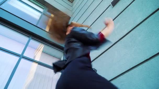 현대 건물 야외 에서 춤을 추는 아름다운 금발의 여자의 낮은 각도 샷 — 비디오