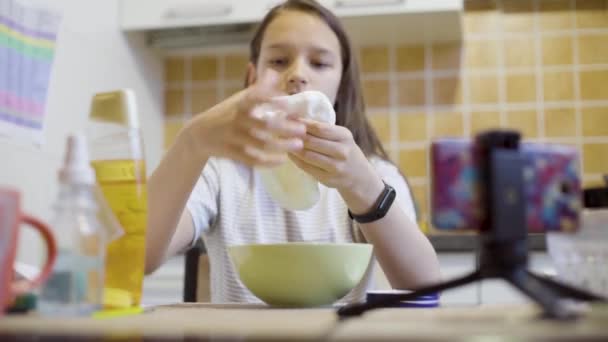 Okul kız germe ve mutfakta ev yapımı kabarık balçık sıkma — Stok video