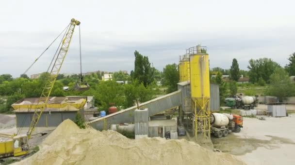 Arc shot of crane claw loading sand into conveyor at concrete factory — Stock Video