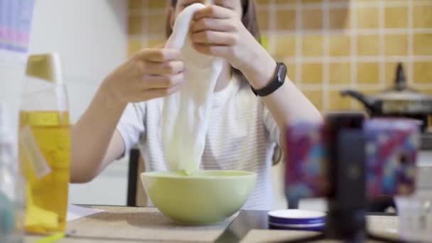 Tiener meisje knijpende en spelen met zelfgemaakte witte slime — Stockvideo