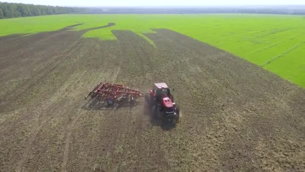 Повітряна частина червоного трактора, що обертається на оранці сільськогосподарського поля — стокове відео