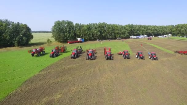 Antenn för grupp av röda jordbruksmaskiner ridning tillsammans på plöjde fält — Stockvideo
