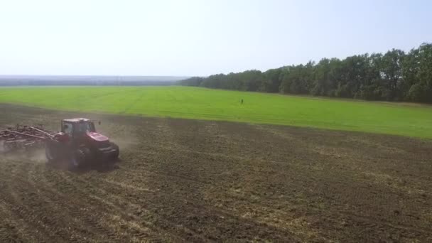 Антенна красных тракторов, вспахивающих почву ранней весной — стоковое видео