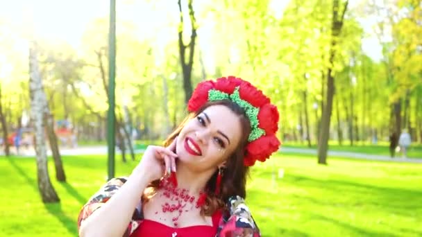 Portrait de femme en costume lumineux et avec cercle de fleurs effectue danse folklorique — Video