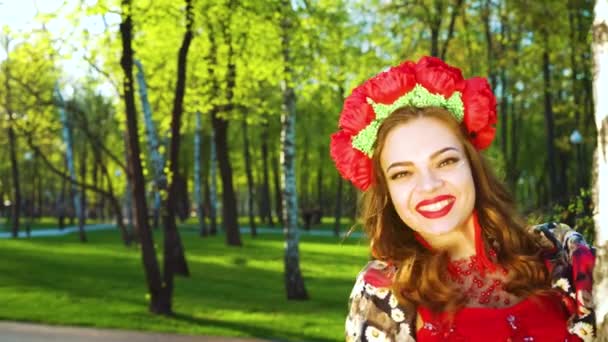 Lens flare on pretty young woman in folk styled costume peeking out from birch — Stock Video
