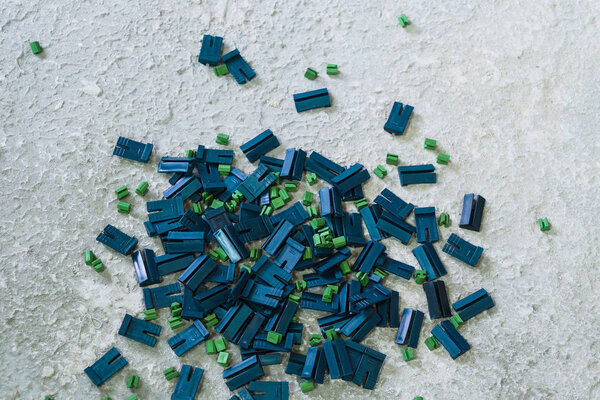 Крупный план синих и зеленых пластиковых клипсов, лежащих на грубой поверхности
