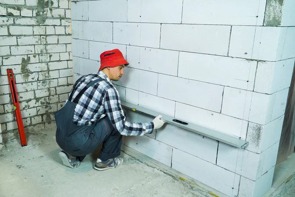 Bauunternehmer überprüft Qualität der Porenbetonsteinmauer mit Baulineal — Stockfoto