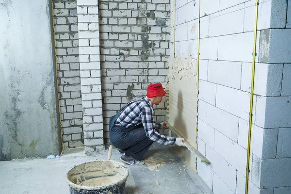 blok duvara sıva onun hunkers üzerinde oturan oluşturucu