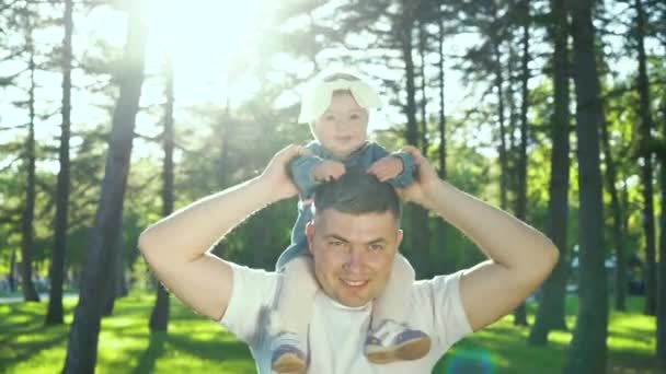 Lente destello en sonriente padre sosteniendo su hija pequeño en hombros al aire libre — Vídeos de Stock