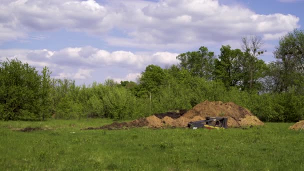 Kharkiv, Oekraïne-mei 06, 2019: graafmachine graven grond in groen landschap — Stockvideo