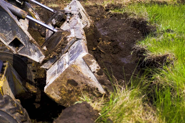 excavator bucket digging pit during earth works