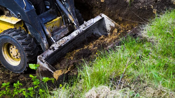 Vista parziale della fossa di scavo del mini caricatore sporco durante i lavori di terra — Foto Stock