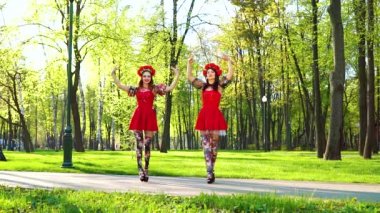 parlak kostümleri iki kadın dansçılar güneşli parkta halk dansları gerçekleştirmek