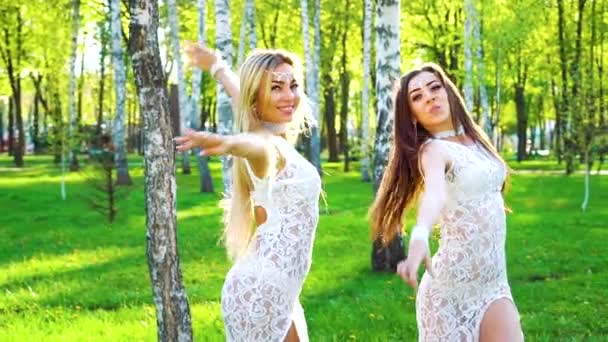 Rayons du soleil sur les femmes blondes et brunes en costumes similaires dansant dans le parc ensoleillé — Video