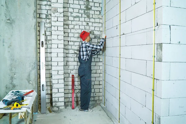 Homem em desgaste de trabalho instalação de trilhos de metal na parede do bloco de concreto aerado — Fotografia de Stock