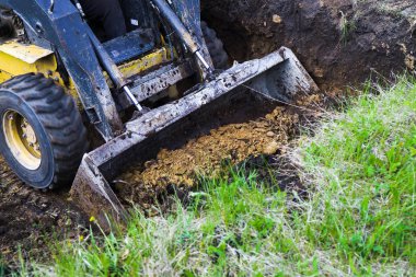 toprak ta kahverengi topraklı buldozer kova ön planda yeşil çim ile çalışır