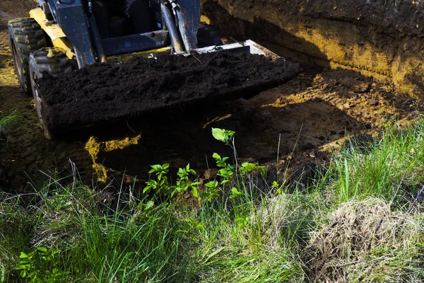 Beskuren bild av rörig bulldozer med jord i sin hink under utgrävningsarbeten — Stockfoto