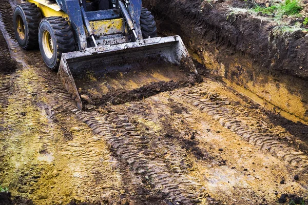 Vista parziale di mini caricatore in fango in piedi nella fossa durante i lavori di scavo — Foto Stock