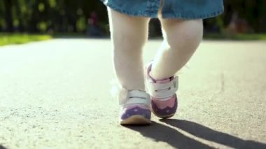 anne ve babası ile güneşli parkta yola basarak yürümeye başlayan kız ayakları düşük çekim