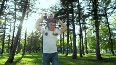 lens parlaması ile açık havada omuzlarında onun bebek kız tutarak baba güneş ışığı