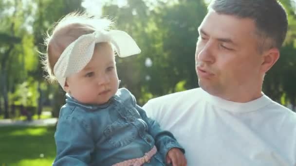 Ηλιοφάνεια για ευτυχισμένο πατέρα κρατώντας το μωρό κορίτσι του περπατώντας στο καλοκαιρινό πάρκο — Αρχείο Βίντεο