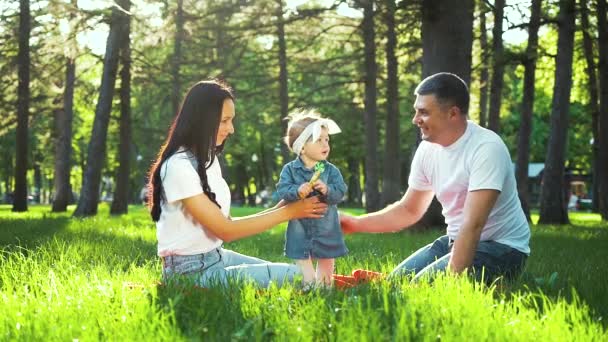 Padres felices con hija pequeña juntos en la hierba verde en el jardín — Vídeos de Stock