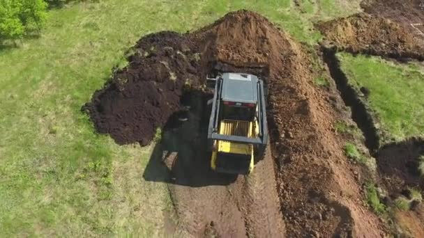 Antenne van bulldozer en graafmachine graven Fundatie pit op grasveld — Stockvideo