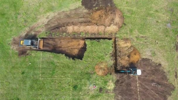 Uppifrån och ned av bulldozer och grävskopa grävnings grop enligt markering på marken — Stockvideo