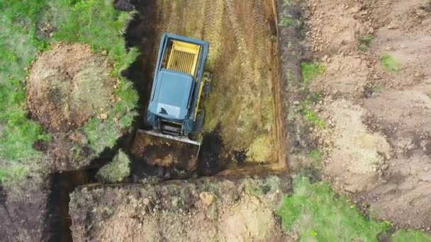 Arriba hacia abajo de mini cargador cava el suelo en el campo herboso para la nueva cimentación de la casa — Vídeos de Stock