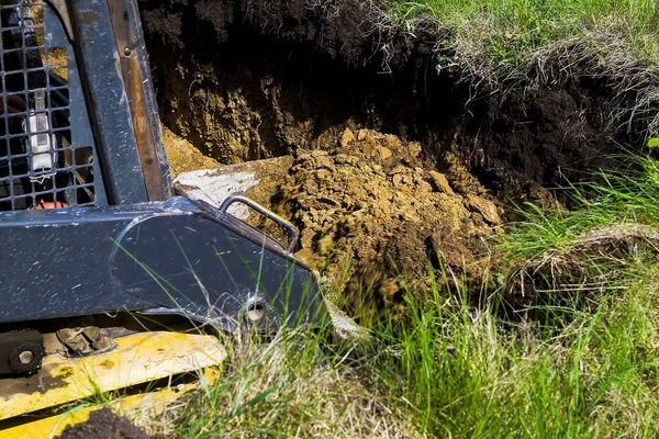 Vue recadrée d'une excavatrice creusant une fosse de fondation dans un champ herbeux à la campagne — Photo