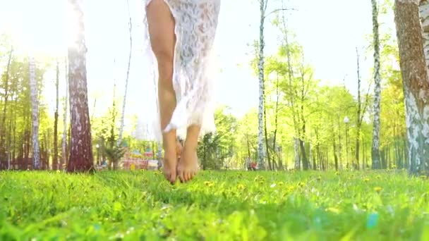 Piernas de mujer en vestido sensual bailando descalzo sobre hierba verde con destello de lente — Vídeos de Stock