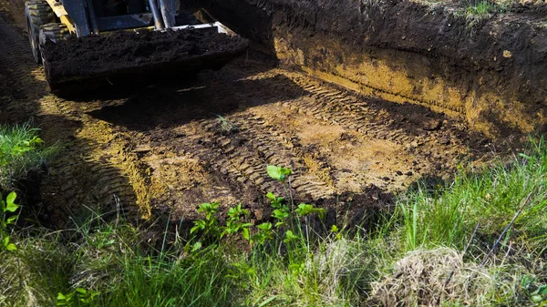 Vista cortada de mini carregador em trabalhos de escavação em área gramada no campo — Fotografia de Stock