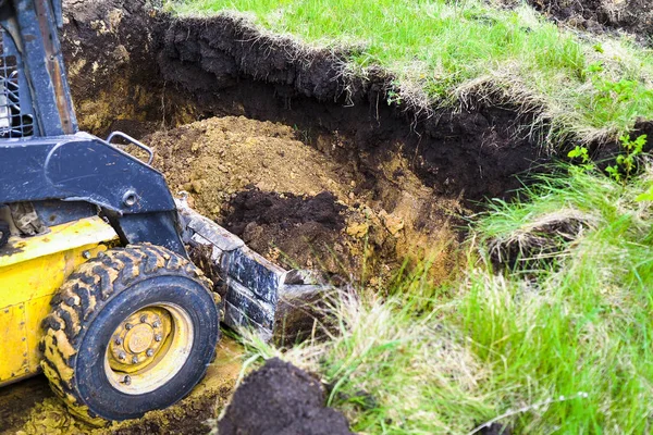 kazı çalışmaları sırasında kovasında toprak bulunan buldozerin kırpılmış görünümü