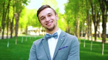 mavi takım elbise li mutlu genç adamın portresi ve kameraya gülen papyon