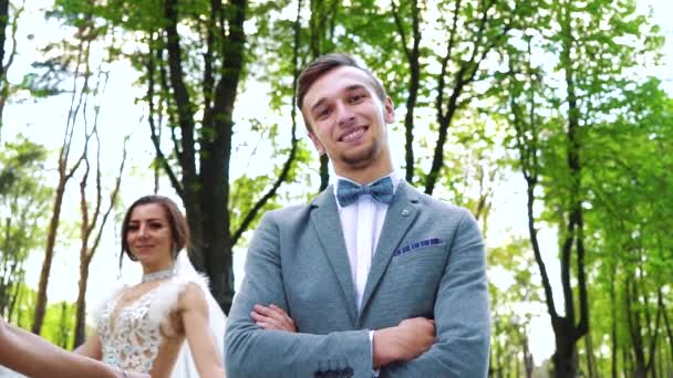 Low angle shot of smiling groom standing still and brides walking around him — Stock Video