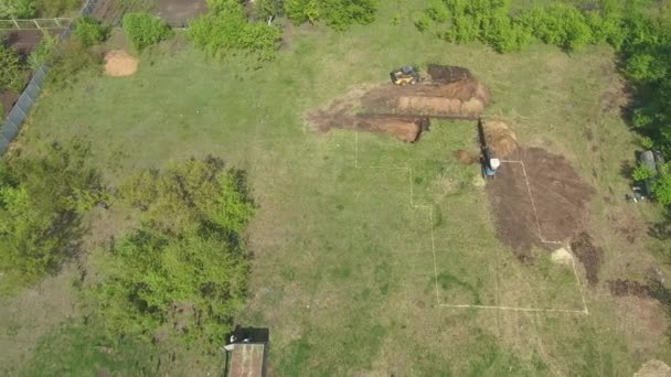 Antenn för att gräva stiftelse grop för nya hus med mini Loader och grävmaskin — Stockvideo