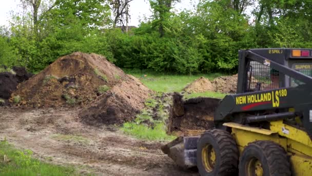 Kharkiv, Ukraine - May 06, 2019: mini loader digs trench in grassy countryside — Stock Video