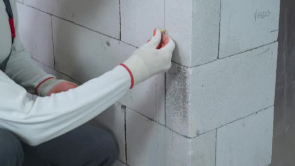 Inclinación hacia arriba tiro de trabajador insertar clavijas en agujeros perforados en la pared del bloque — Vídeo de stock