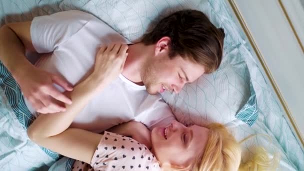 Closeup rotating camera over two smiling lovers in bed in the morning — Stock Video