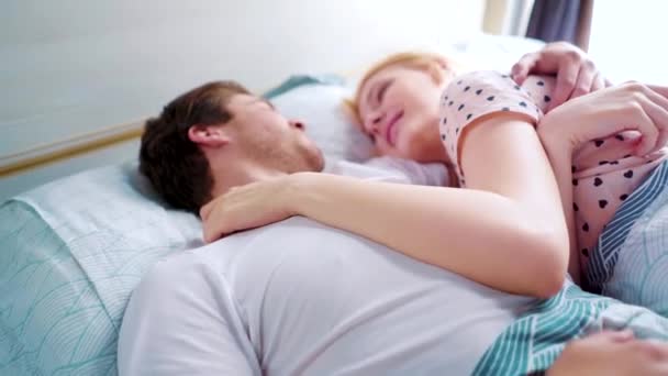 Mladý muž a žena v posteli v noci nosí úsměv na sebe v dopoledních hodinách — Stock video