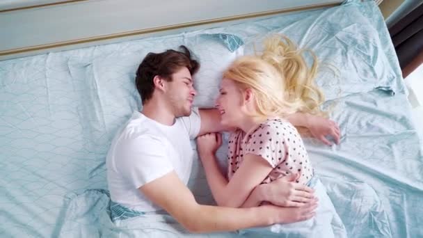 Zoom haut vers le bas jeune couple souriant au lit le matin — Video