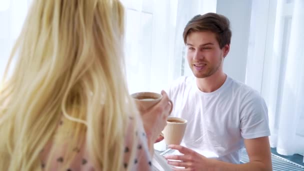 Genç yakışıklı adam yerde oturuyor ve sarışın kadınla sabah kahvesini içiyor. — Stok video