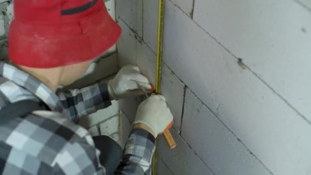 Tiro de ângulo alto do trabalhador fixando trilho de metal com braçadeira na parede do bloco de concreto — Vídeo de Stock