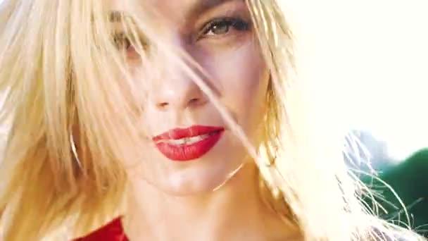 Портрет крупным планом красивой блондинки с красной помадой на солнце снаружи — стоковое видео