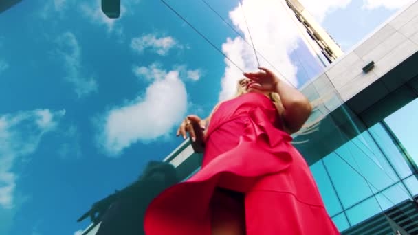 Низький кут зйомки танцюючої жінки біля дзеркальної поверхні, що відбиває хмари — стокове відео