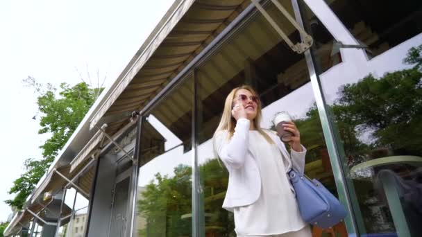 Χαμηλή γωνία της επιχείρησης γυναίκα που μιλά στο smartphone κατά τη διάρκεια της διακοπής του καφέ έξω — Αρχείο Βίντεο