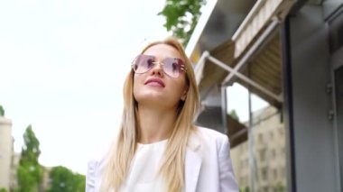 genç şık sarışın kadın kamera bakarak ve sokakta yürürken düşük açılı çekim