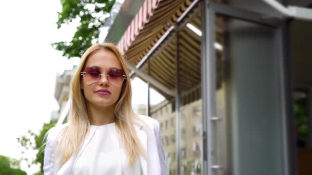 Niski kąt całkiem blond kobieta w okulary spacerowe w dół ulicy — Wideo stockowe